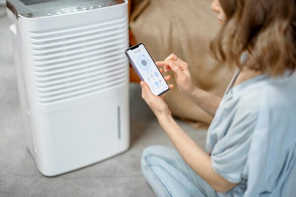 Woman sitting near air purifier and moisturizer appliance